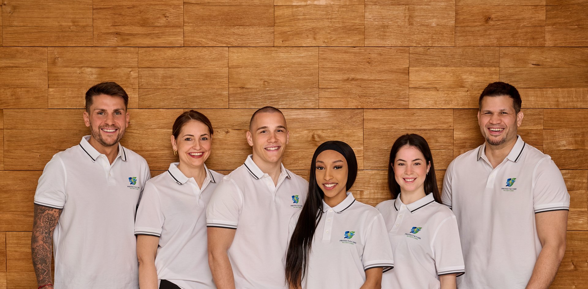 Sechs lächelnde Teammitglieder vor Holzwand